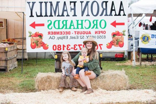 a mom and daughters sitting on hay bails