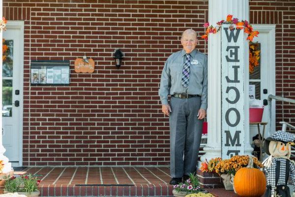 A man standing next to a fall welcome sign